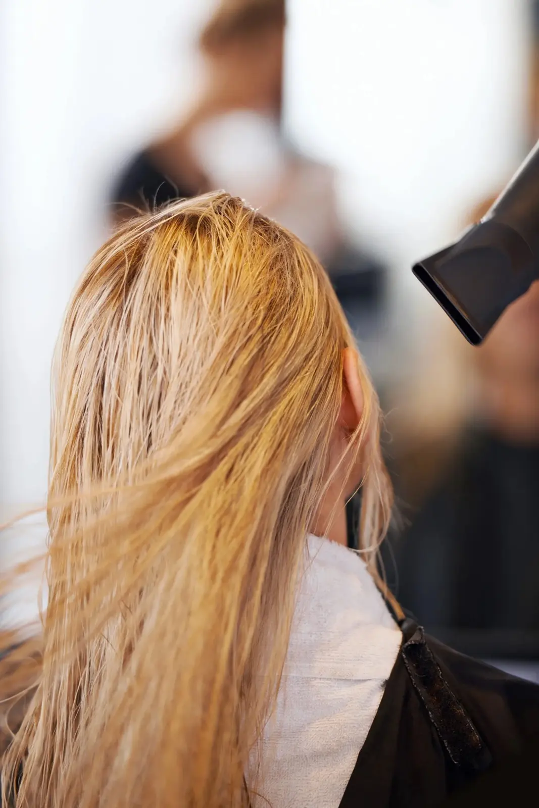 Stylist blow-drying a client's long blonde hair at Sweet T Salon